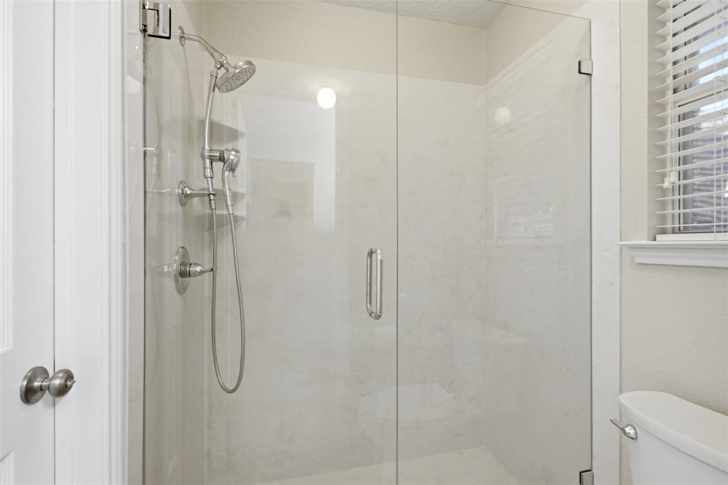4218 Glistening Spring Rowlett, TX 75088 - Photo 27 of 39 Glass-enclosed shower featuring a handheld showerhead, brushed nickel fixtures, and light-toned tile surround