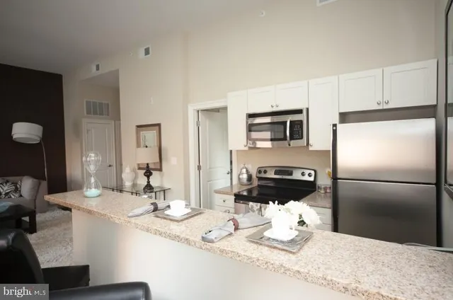 a kitchen with granite countertop wooden floors a stove and white cabinets