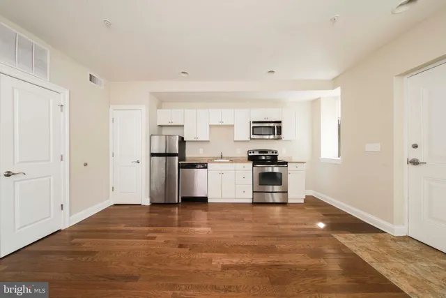 a kitchen with granite countertop a stove top oven a sink dishwasher and a microwave with wooden floor