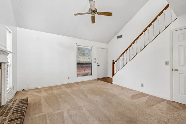 a view of an empty room with a chandelier fan