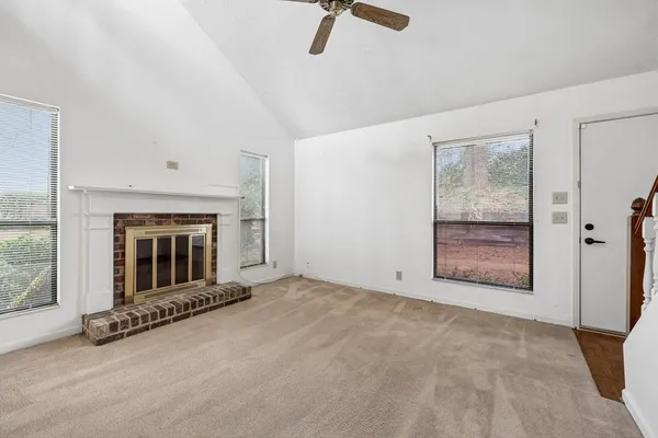 an empty room with windows fireplace and bathroom