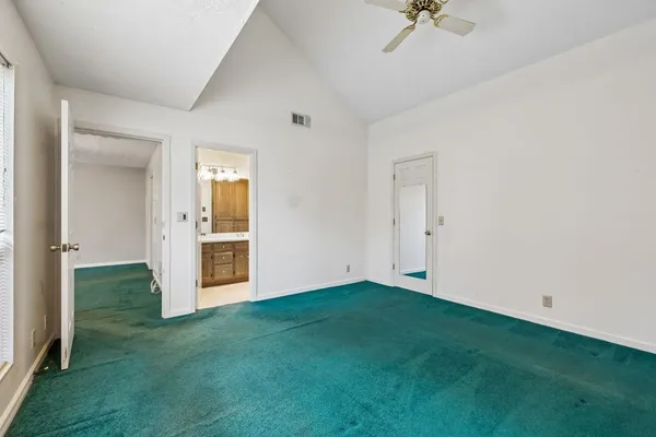 an empty room with chandelier fan and windows