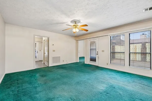 an empty room with a chandelier fan and closet area