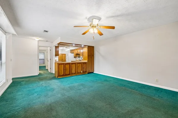 a view of an empty room with window and cabinet area