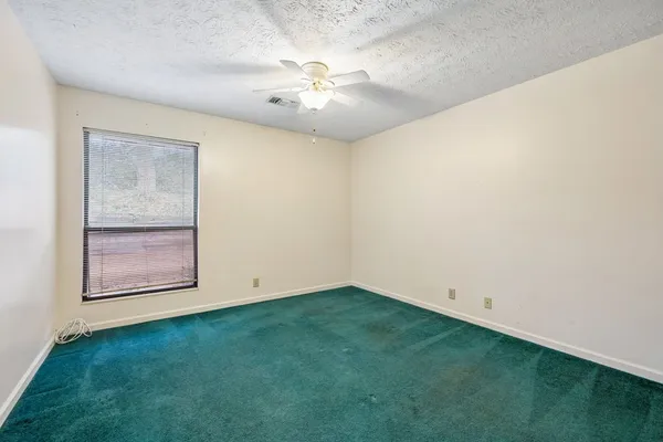 a view of an empty room with chandelier fan and fire place