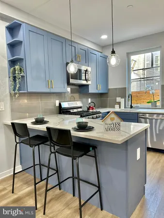a kitchen with stainless steel appliances granite countertop a sink a stove and chairs