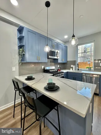 a kitchen with a stove a refrigerator a sink a dining table and chairs