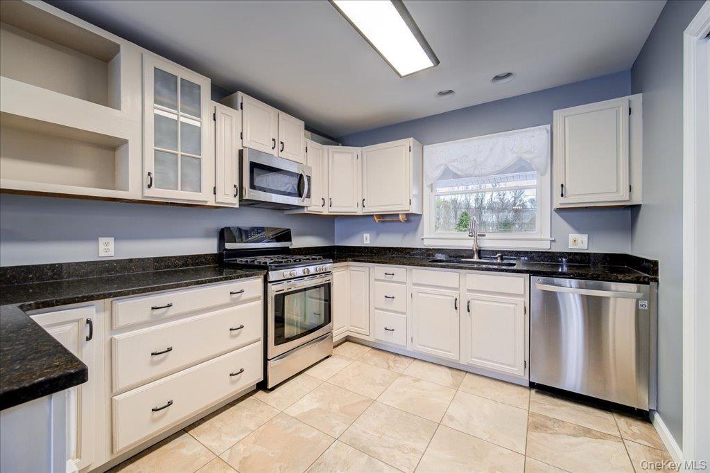 157 Brewer Road Newburgh, NY 12550 - Photo 16 of 50 The kitchen features white cabinetry with black hardware, dark countertops, and stainless steel appliances including a range, microwave, and dishwasher