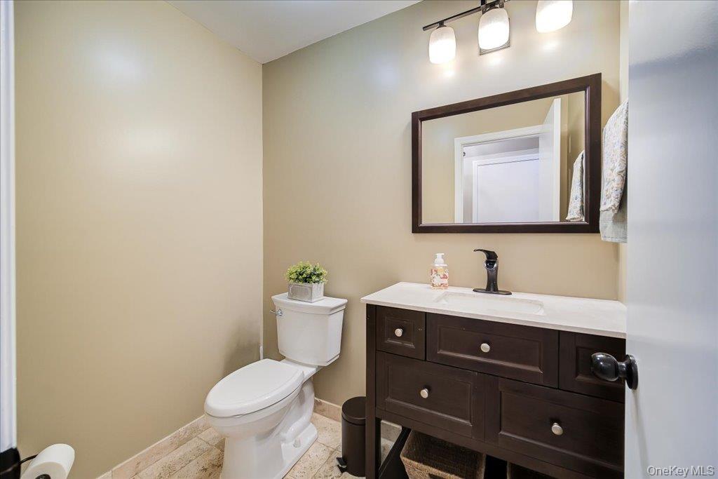 157 Brewer Road Newburgh, NY 12550 - Photo 18 of 50 Bathroom featuring a dark wood vanity with a white countertop and a mirror, a modern three-light fixture, and light-colored tiled flooring