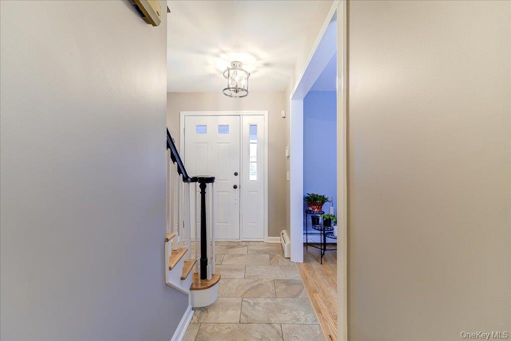157 Brewer Road Newburgh, NY 12550 - Photo 20 of 50 Inviting entryway featuring tile flooring, a white paneled front door with sidelights, and a staircase with white risers and a dark wood handrail