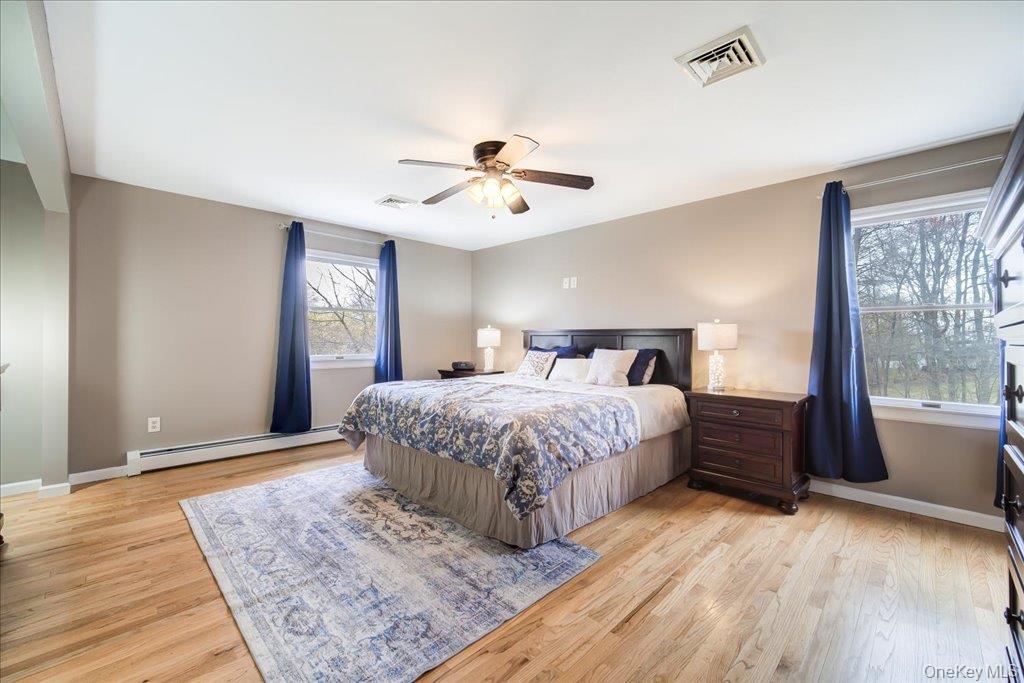157 Brewer Road Newburgh, NY 12550 - Photo 21 of 50 This bedroom features hardwood floors, light neutral wall colors, a ceiling fan, and large windows with views of trees