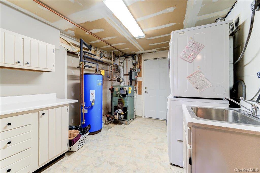 157 Brewer Road Newburgh, NY 12550 - Photo 37 of 50 The utility area features a laundry sink, white cabinetry with countertops, and a stacked washer and dryer