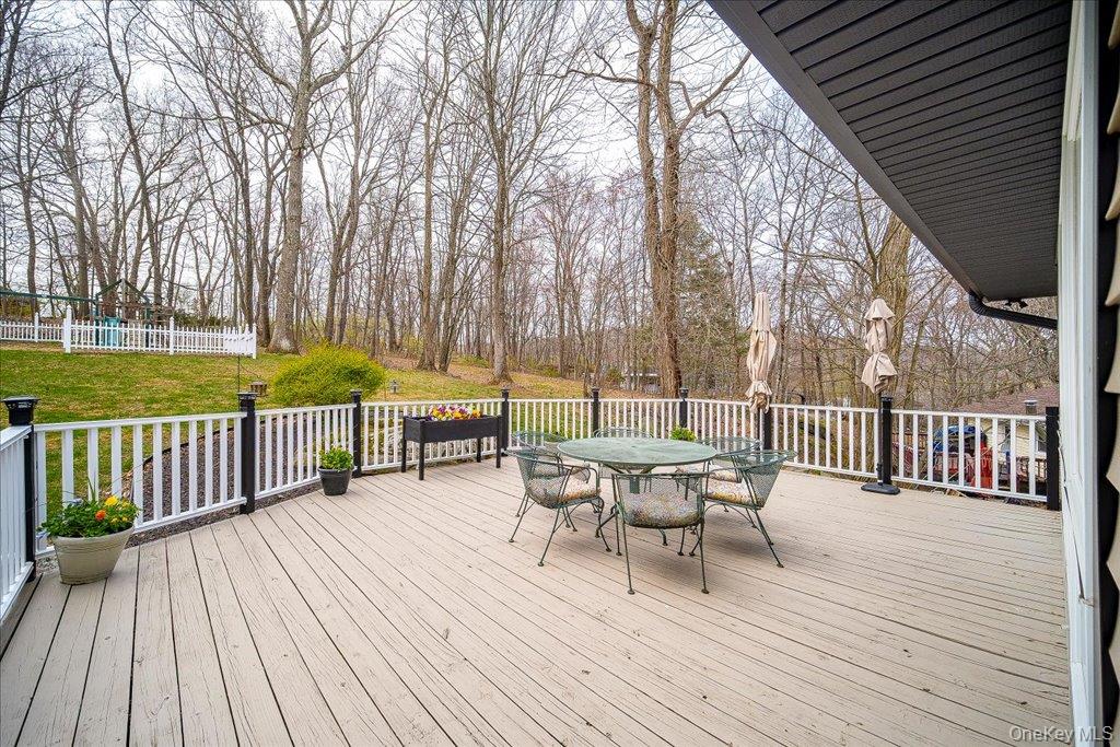 157 Brewer Road Newburgh, NY 12550 - Photo 39 of 50 The property features an outdoor deck with white railings and black posts, overlooking a grassy area with mature trees