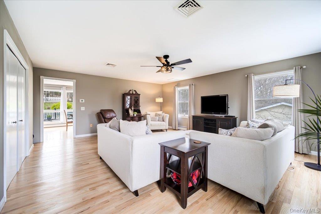 157 Brewer Road Newburgh, NY 12550 - Photo 7 of 50 Spacious living area featuring light-toned hardwood floors, a ceiling fan, and large windows providing natural light