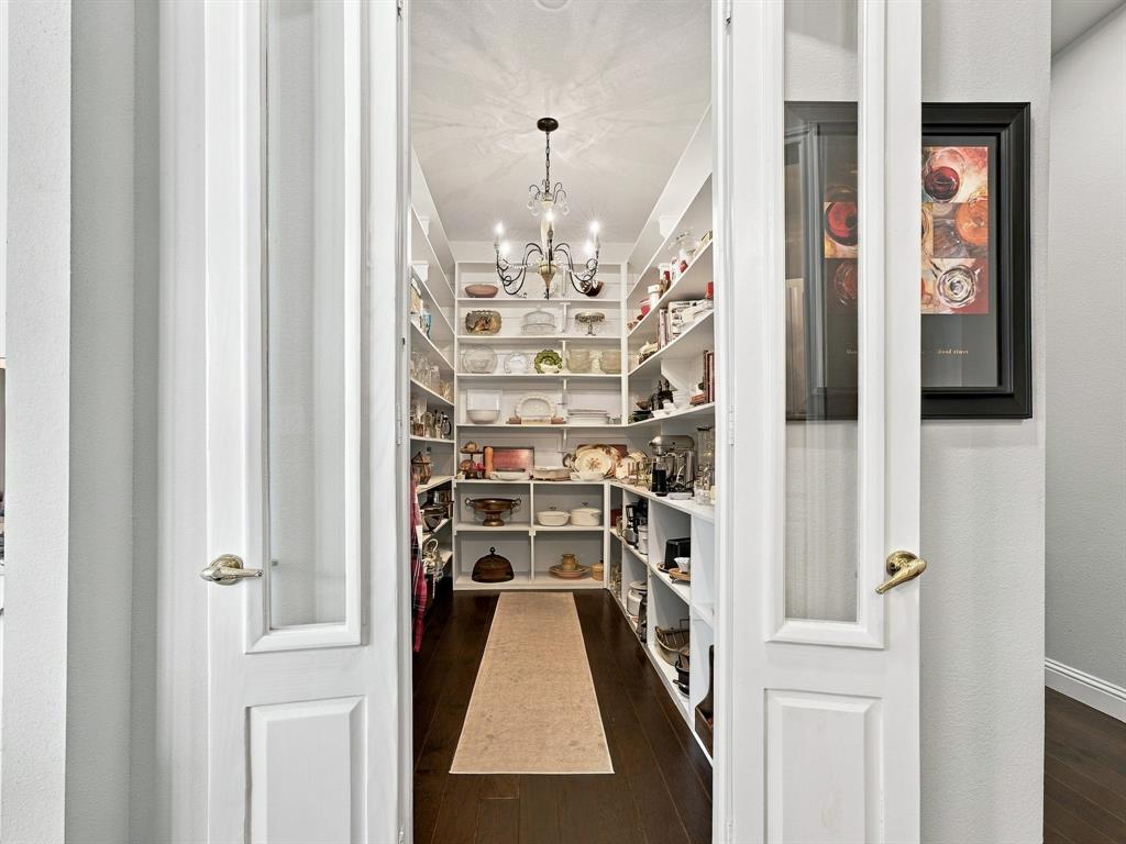 330 Rolling Bnd Road Alvord, TX 76225 - Photo 17 of 36 Walk-in pantry featuring extensive built-in shelving, dark wood-finish flooring, a decorative chandelier, and paneled French doors