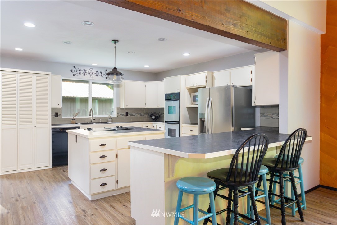 2291 East Pole Road Everson, WA 98247 - Photo 8 of 40 a kitchen with granite countertop a refrigerator a stove a dining table and chairs with wooden floor