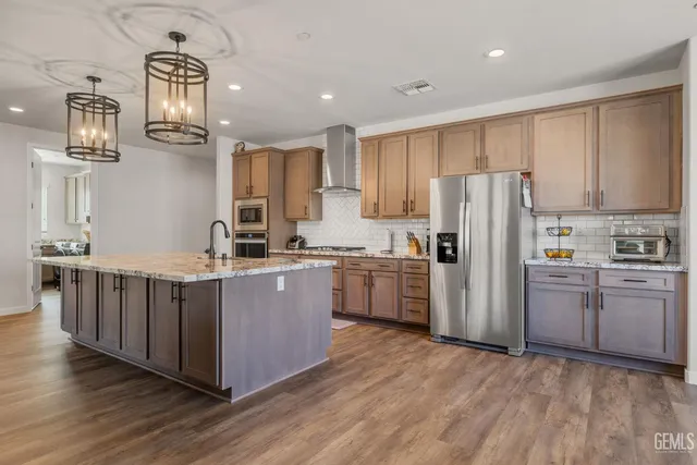 a kitchen with stainless steel appliances granite countertop a refrigerator a stove top oven a sink and dishwasher