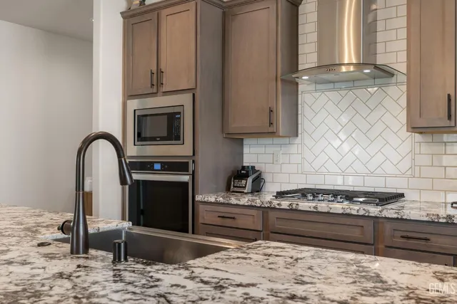 a kitchen with stainless steel appliances granite countertop a stove a sink and a microwave