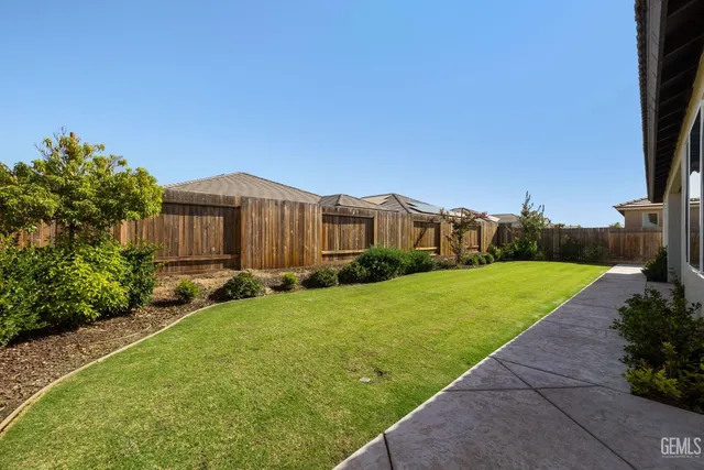 a view of a backyard with potted plants and large tree