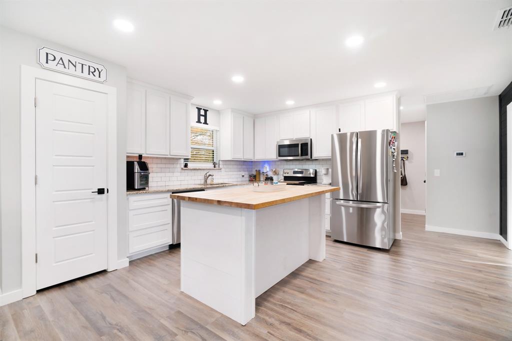 324 Private Road Paris, TX 75462 - Photo 6 of 15 a kitchen with stainless steel appliances a refrigerator a stove a sink cabinets and wooden floor