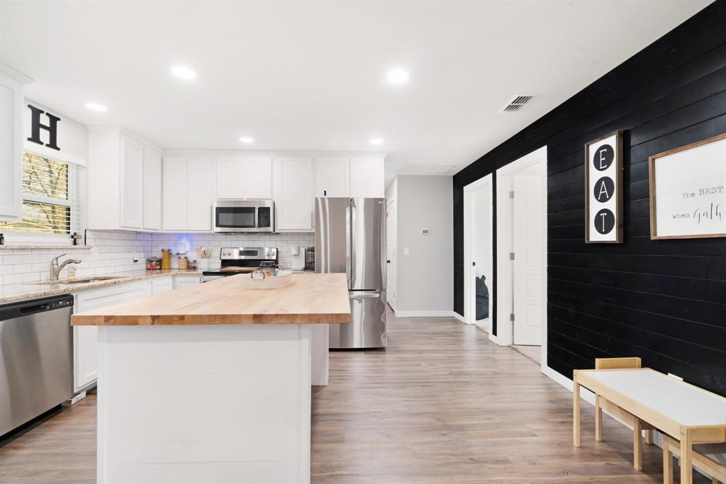 324 Private Road Paris, TX 75462 - Photo 7 of 15 a kitchen with stainless steel appliances kitchen island granite countertop a refrigerator a stove top oven a sink and dishwasher with wooden floor