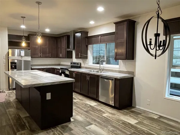 a kitchen with kitchen island granite countertop a sink and a stove with wooden floor