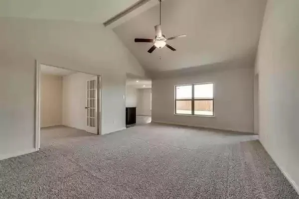 an empty room with chandelier fan and windows