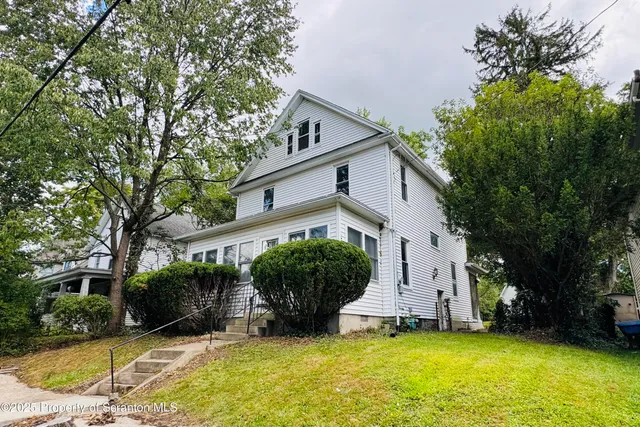 a view of a house with a yard and large tree
