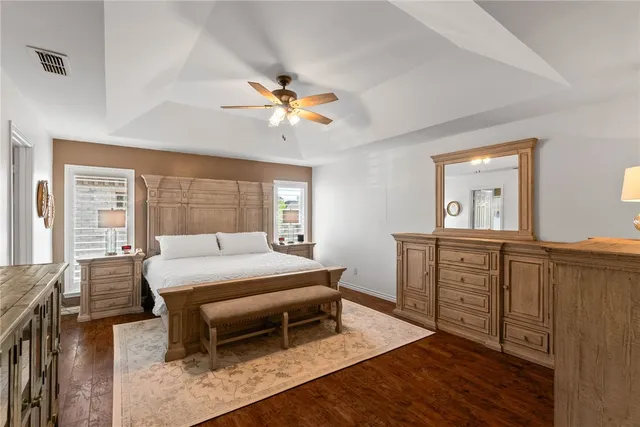 a bedroom with a bed and a dresser with wooden floor