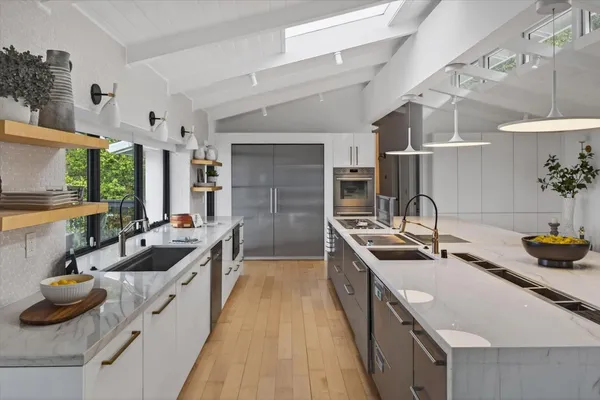 a kitchen with stainless steel appliances granite countertop a refrigerator a stove a sink a dining table and chairs