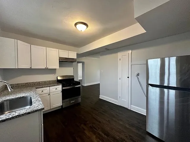 a kitchen with granite countertop a refrigerator stove and sink