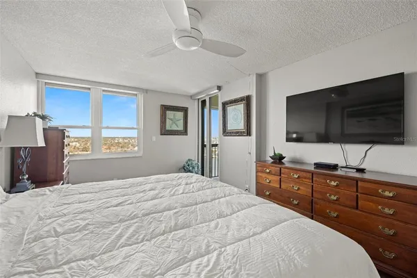 a bedroom with a bed a flat screen tv and a chandelier
