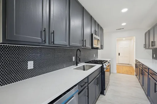 a kitchen with granite countertop a sink and white cabinets
