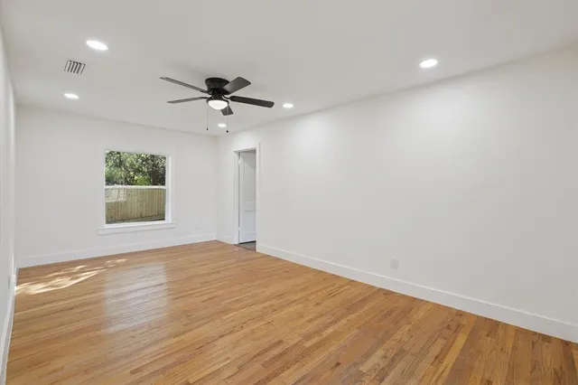 a view of an empty room with a window and wooden floor