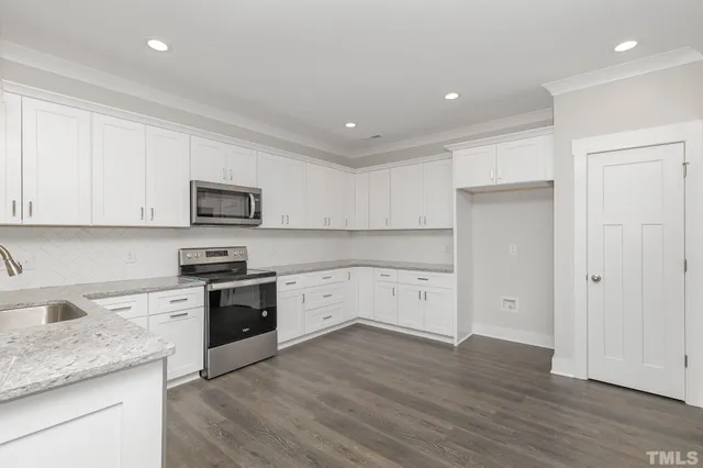a kitchen with stainless steel appliances granite countertop a stove a sink and white cabinets