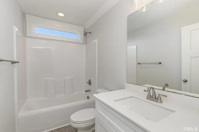 a bathroom with a granite countertop bathtub shower sink vanity mirror and toilet