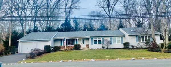 a view of a white house with a yard plants and large tree