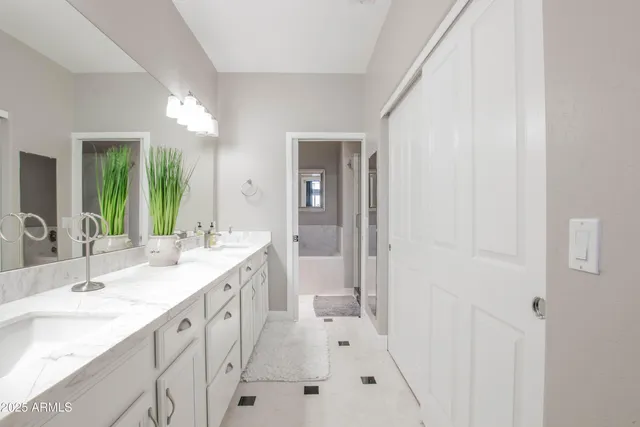 a spacious bathroom with a double vanity sink a mirror and a bathtub
