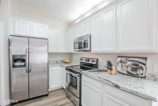 a kitchen with granite countertop stainless steel appliances a refrigerator a stove and cabinets