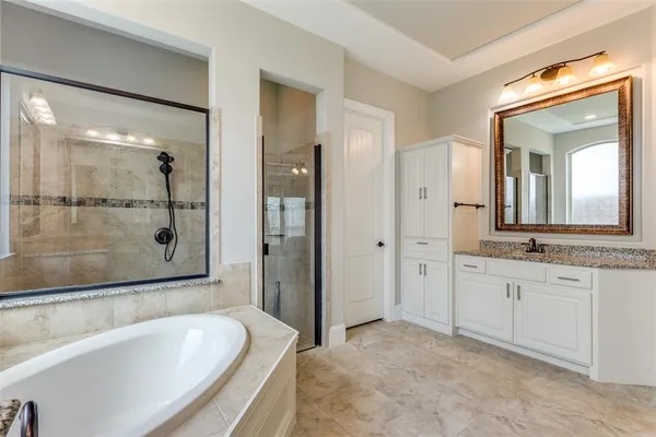 a large spacious bathroom with a granite countertop tub shower and mirror