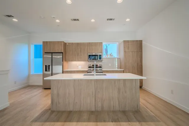 a large kitchen with stainless steel appliances a large counter top a stove and a refrigerator