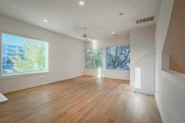 an empty room with wooden floor and windows