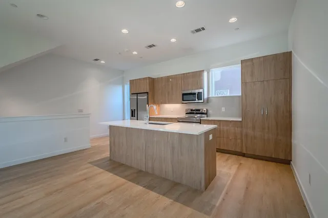 a kitchen with kitchen island granite countertop wooden cabinets a sink a refrigerator and a stove