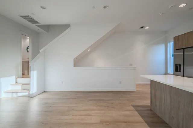 a view of kitchen and empty room with wooden floor
