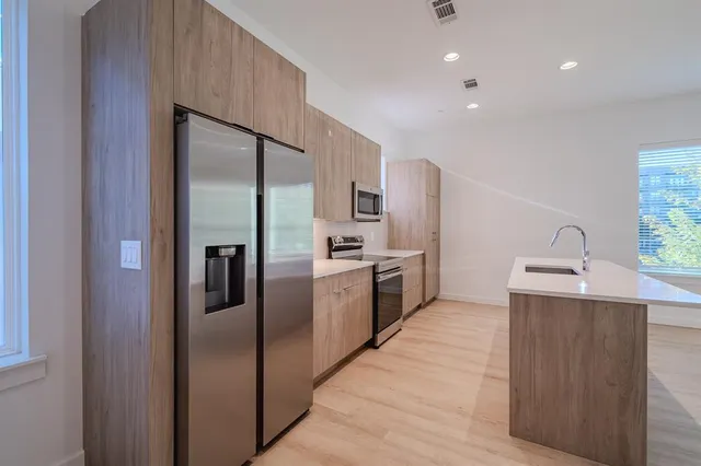 a large kitchen with granite countertop a large counter top stainless steel appliances and cabinets