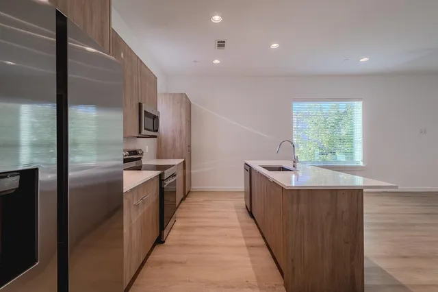 a large kitchen with kitchen island a large counter top space a sink stainless steel appliances and windows