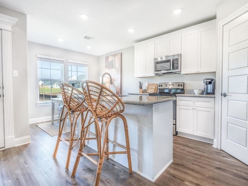 23906 Peppermint Street Elberta, AL 36530 - Photo 6 of 14 Kitchen with an island with sink, white cabinets, stainless steel appliances, light stone counters, and dark wood-style flooring