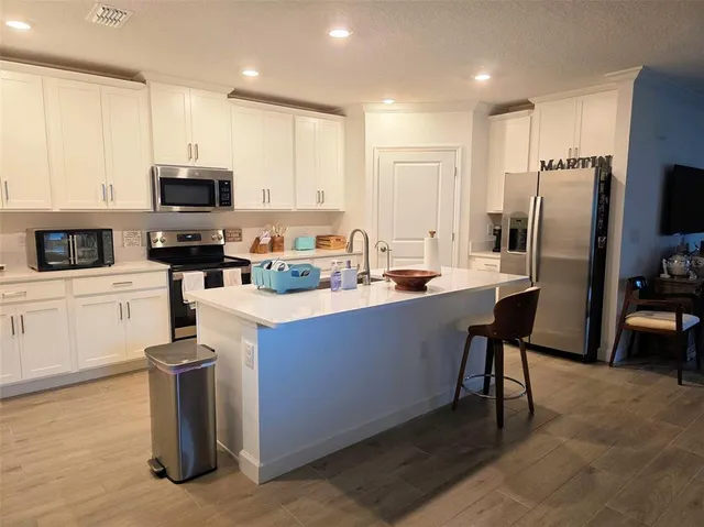 a kitchen with stainless steel appliances a sink a stove a microwave a refrigerator and cabinets