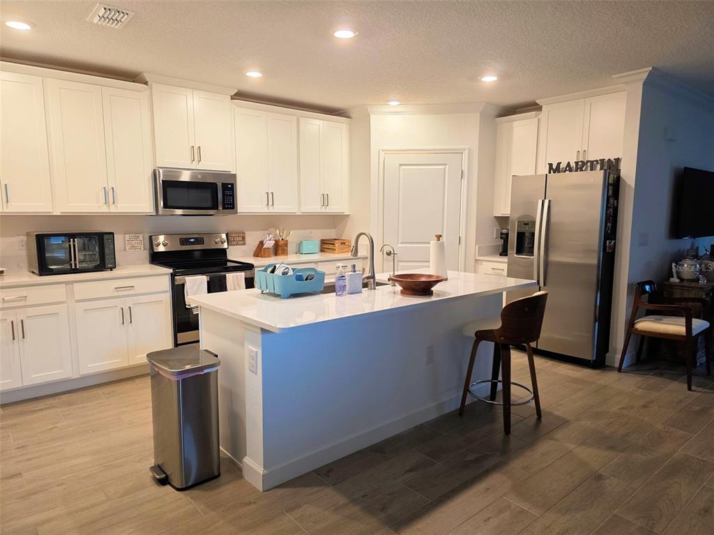 16890 Forge Surf Street Land O Lakes, FL 34638 - Photo 20 of 26 a kitchen with stainless steel appliances a sink a stove a microwave a refrigerator and cabinets