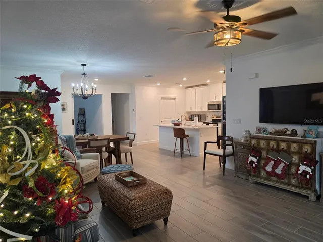 a living room with furniture a flat screen tv and a chandelier